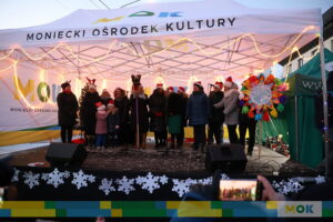 Liczna grupa osób śpiewająca na scenie.