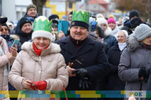 Na pierwszym planie uśmiechnięta kobieta z mężczyzną na tle dużej grupy ludzi.