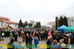 Duże zbiorowisko ludzi zebrane na placu przed kościołem.