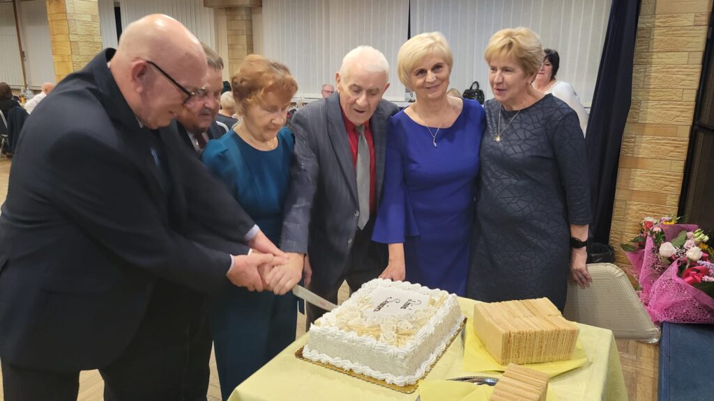 Ludzie w radosnym nastroju dzielą się tortem, tworząc wspólne wspomnienia podczas uroczystości.