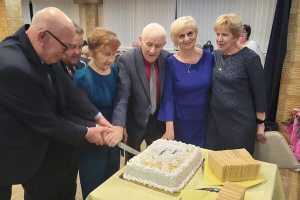 Ludzie w radosnym nastroju dzielą się tortem, tworząc wspólne wspomnienia podczas uroczystości.